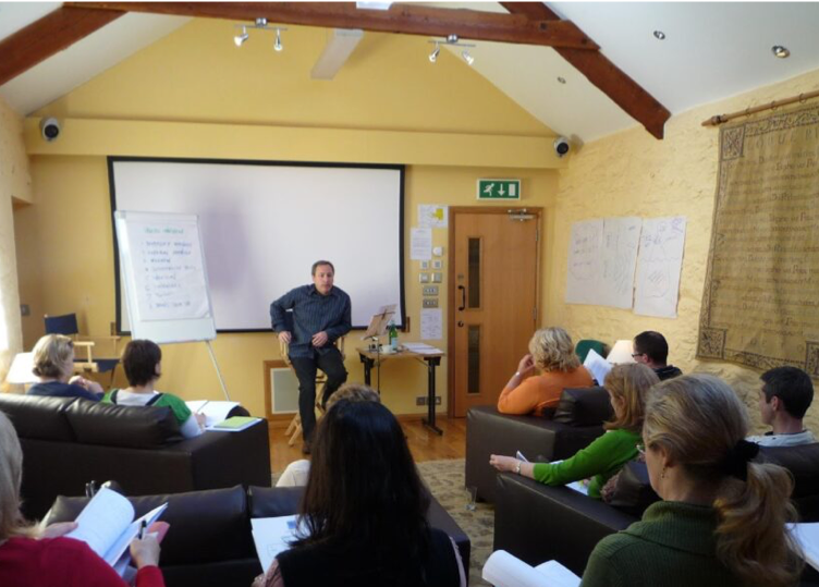 hypnotherapy trainer at front of room with multiple seated people taking notes